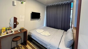 A hotel room with a bed, a TV mounted on the wall, a desk with a chair, and a mirror. - Ijen Menjangan View (Banyuwangi)