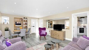 A spacious living area with a modern kitchen, a dining area, and a seating area with purple sofas and a small coffee table. - Countryside Retreat on Surrey/Hampshire Border (Haslemere)