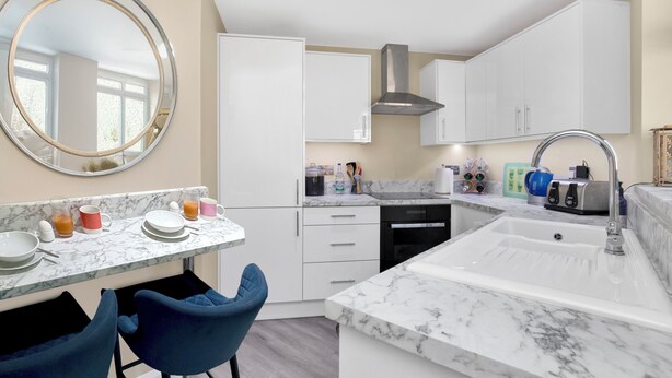 A modern kitchen with white cabinets, a marble countertop, a sink, and a round mirror. - Countryside Retreat on Surrey/Hampshire Border (Haslemere)