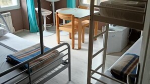 A dormitory room with bunk beds, a small table, and a chair. - Gite D'étape port de Carhaix (Carhaix-Plouguer)