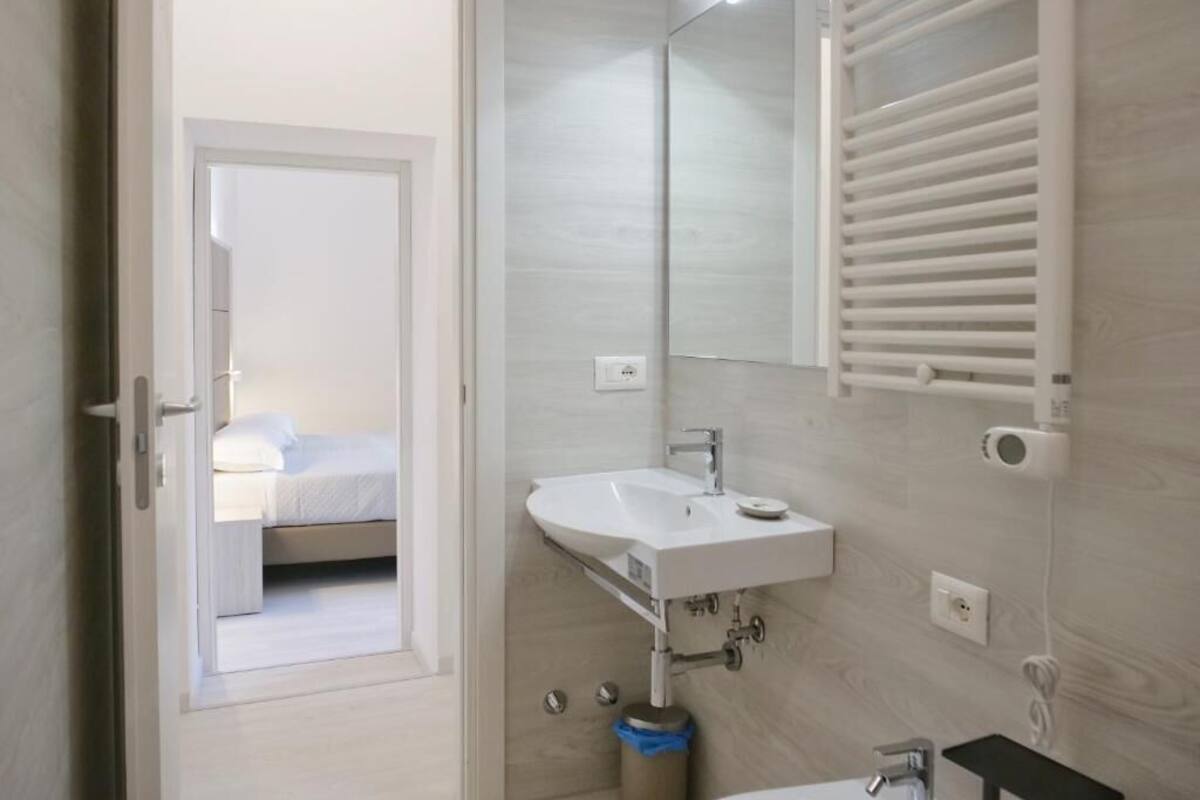 A modern bathroom with a white sink, mirror, and towel rack.