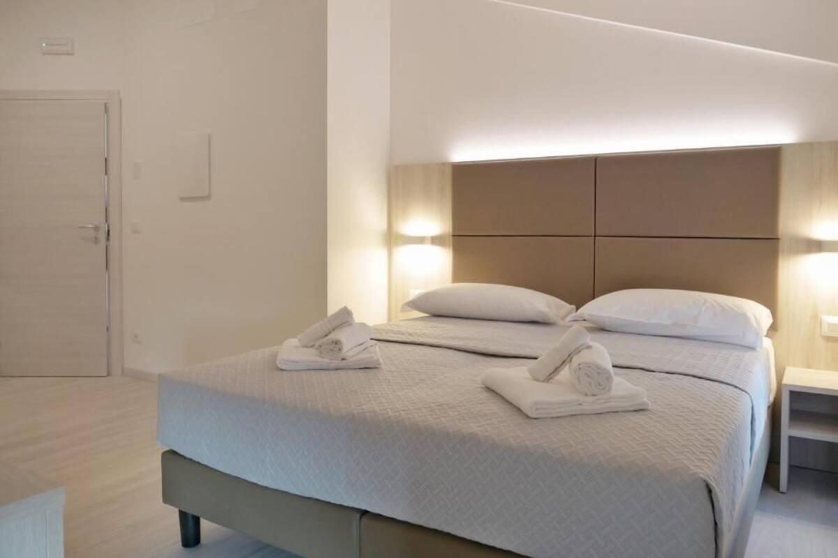 A hotel room with a bed, two bedside tables, and a door.