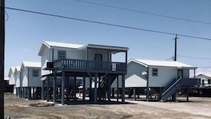 Una fila de casas de dos pisos, con un balcón en la planta baja, conectadas por un paseo techado.
