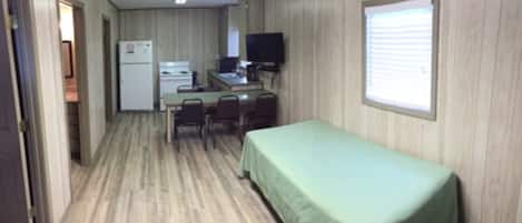 A compact room with a bed, a desk with a computer, a refrigerator, and a television.