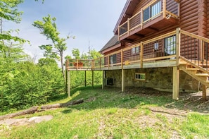 A log cabin with a wooden deck and a stone foundation.