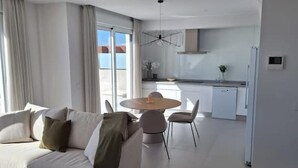 Un salon moderne avec un canapé, une table de salle à manger ronde et une cuisine en arrière-plan.