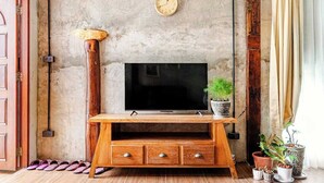 Eine Holzunterhaltungsecke mit Flachbildfernseher, einer Uhr und Topfpflanzen.