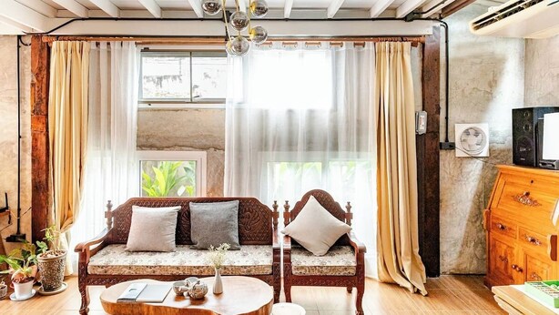 Ein gemütliches Wohnzimmer mit einem Holzsofa, einem runden Couchtisch und einem Fernseher auf einer Holzkommode.
