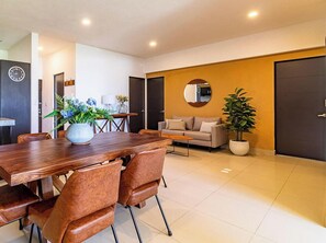 A modern living room with a dining area, a sofa set, a coffee table, and a potted plant.