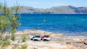 A beach with clear blue water, rocky shore, and mountains in the background. - Holiday Home 'Can Figó' with Sea View, Wi-Fi and Air Conditioning (Alcúdia)
