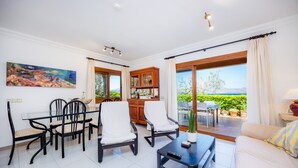 A spacious living area with a dining table, chairs, a sofa, and a coffee table. - Holiday Home 'Can Figó' with Sea View, Wi-Fi and Air Conditioning (Alcúdia)