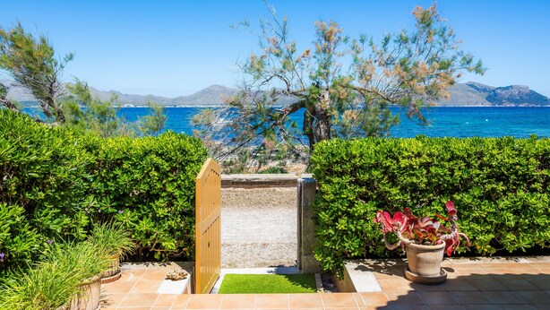 A garden with a wooden gate leading to a patio area with a view of the sea and mountains. - Holiday Home 'Can Figó' with Sea View, Wi-Fi and Air Conditioning (Alcúdia)