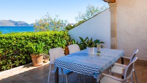 A patio with a table and chairs, potted plants, and a view of the sea. - Holiday Home 'Can Figó' with Sea View, Wi-Fi and Air Conditioning (Alcúdia)