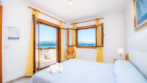 A hotel room with a bed, a chair, a table, and a view of the sea. - Holiday Home 'Can Figó' with Sea View, Wi-Fi and Air Conditioning (Alcúdia)