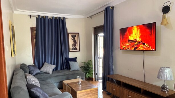 A living room with a sofa, coffee table, TV, and wooden cabinet. - Beautiful 2-bedroom apartment in Muyenga city center in Kampala with Lake View (Kampala)