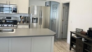 Eine moderne Küche mit Edelstahlgeräten, einer zentralen Kochinsel und einem dunklen Holzserverschrank.