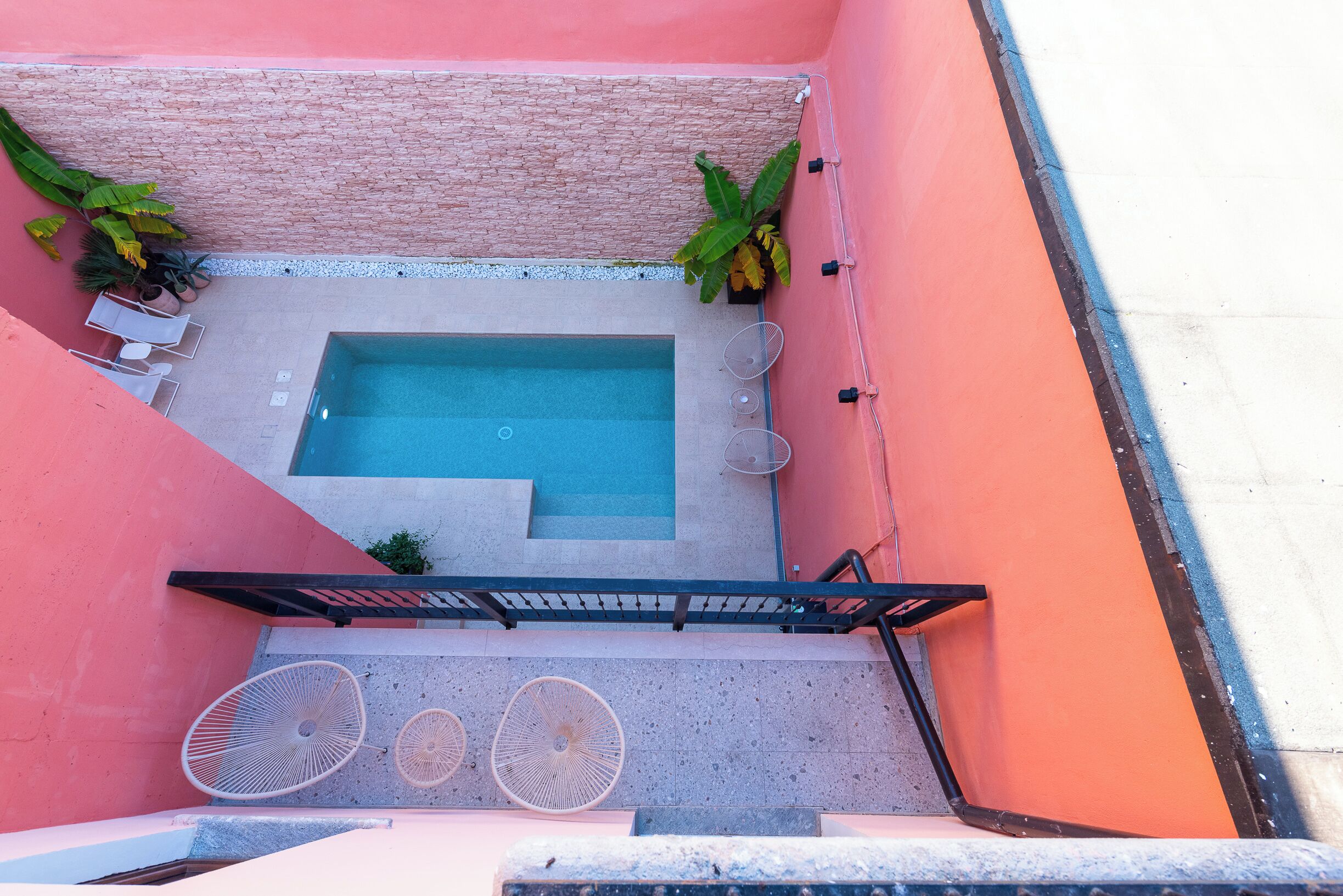 A rooftop pool area with a hot tub, lounge chairs, and umbrellas.