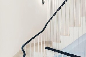 Uma escadaria com corrimão preto e paredes brancas.