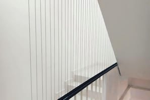 Un escalier avec une rampe noire et des murs blancs.