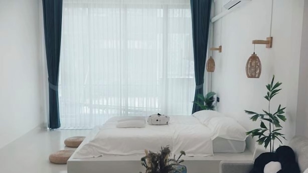 Une chambre à coucher moderne avec un lit, une table de chevet et une plante en pot.