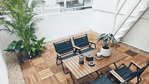 Une terrasse en bois avec une table et des chaises, entourée de plantes en pot.