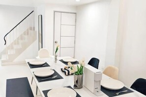 Uma área de refeições moderna com uma mesa comprida, cadeiras e um vaso com flores.