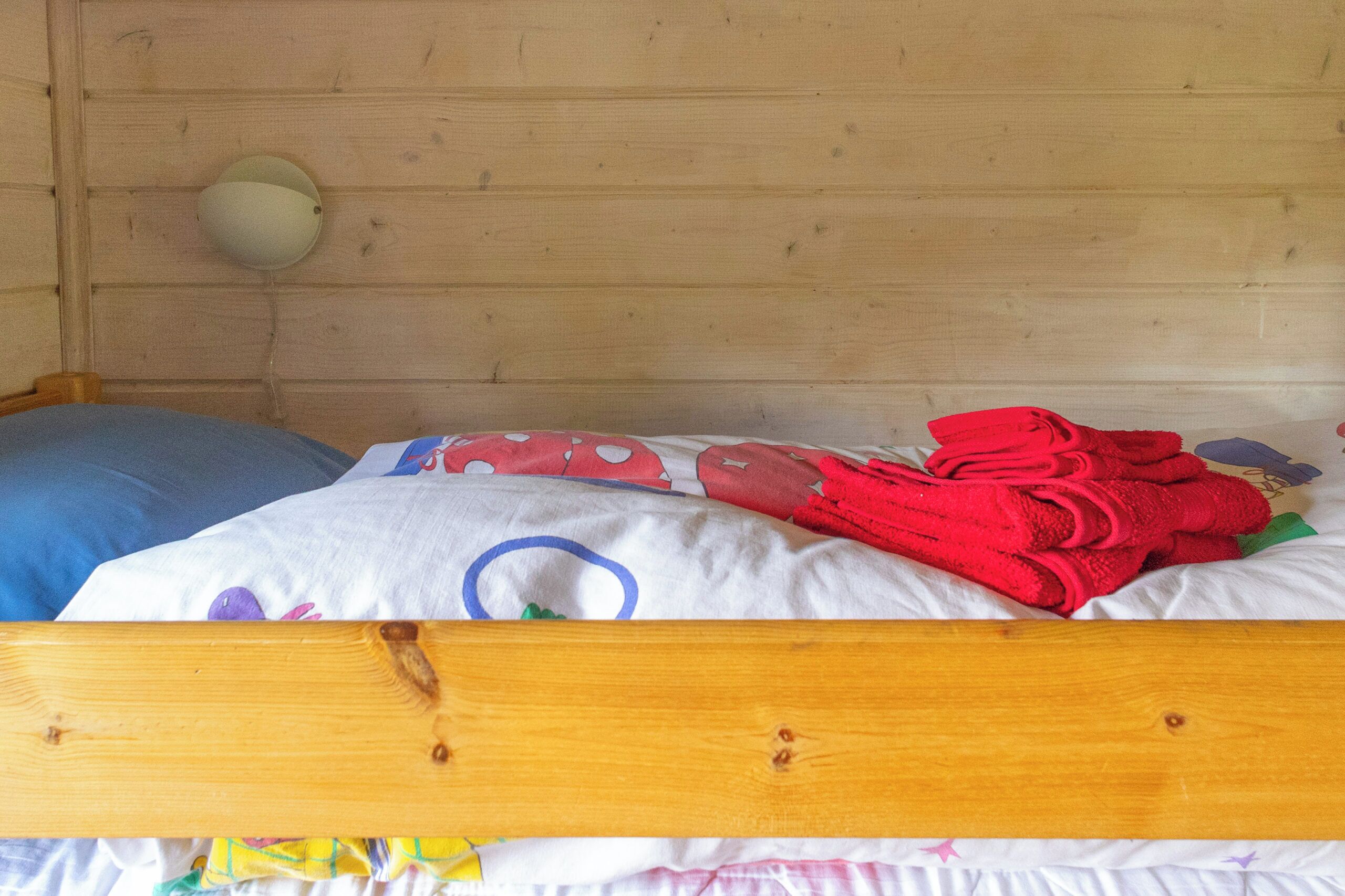 A wooden bunk bed with a white mattress and a blue pillow.