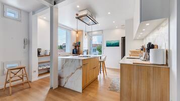 Une cuisine moderne dotée d’un îlot en marbre, de meubles en bois et d’une cuisinière intégrée.