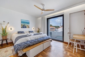 A bedroom with a bed, bedside table, chair, ceiling fan, and a view through a glass door. - Villa Alekatele, Elegant Rental, 100 m from the Beach - 1700 (La Tranche sur Mer)