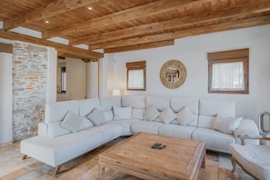 Una sala de estar moderna con un amplio sofá en forma de L, una mesa de centro de madera y una pared de piedra.