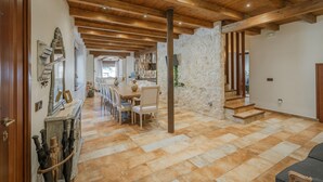 Un intérieur spacieux avec un haut plafond en bois, des murs en pierre et un coin repas comprenant des chaises et une table.