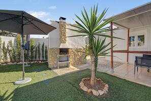A backyard with a stone fireplace, a palm tree, and a patio area. - Holiday Home 'El Encanto De Ronda' with Mountain View, Private Pool and Wi-Fi (Ronda)