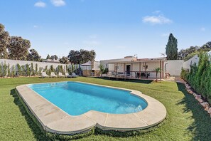A swimming pool with a stone deck, surrounded by a well-maintained lawn and a patio area with outdoor furniture. - Holiday Home 'El Encanto De Ronda' with Mountain View, Private Pool and Wi-Fi (Ronda)