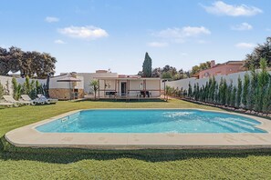 A swimming pool with a patio area, a stone wall, and a tall tree in the background. - Holiday Home 'El Encanto De Ronda' with Mountain View, Private Pool and Wi-Fi (Ronda)