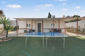 An outdoor ping pong table set up in a covered area with chairs and a small building in the background. - Holiday Home 'El Encanto De Ronda' with Mountain View, Private Pool and Wi-Fi (Ronda)