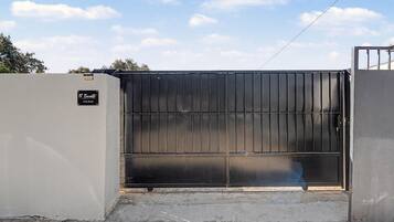 A gated entrance with a metal gate and a sign that reads 'El Encanto Casa Rural.'