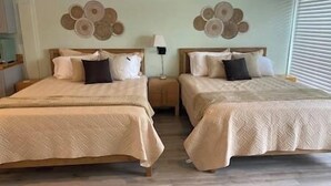 A double room with two beds, each with a headboard, a bedside table, and a lamp.