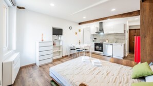 Ein kleines Zimmer mit Bett, einer Küchenzeile, einem Essbereich und einem Fernseher.