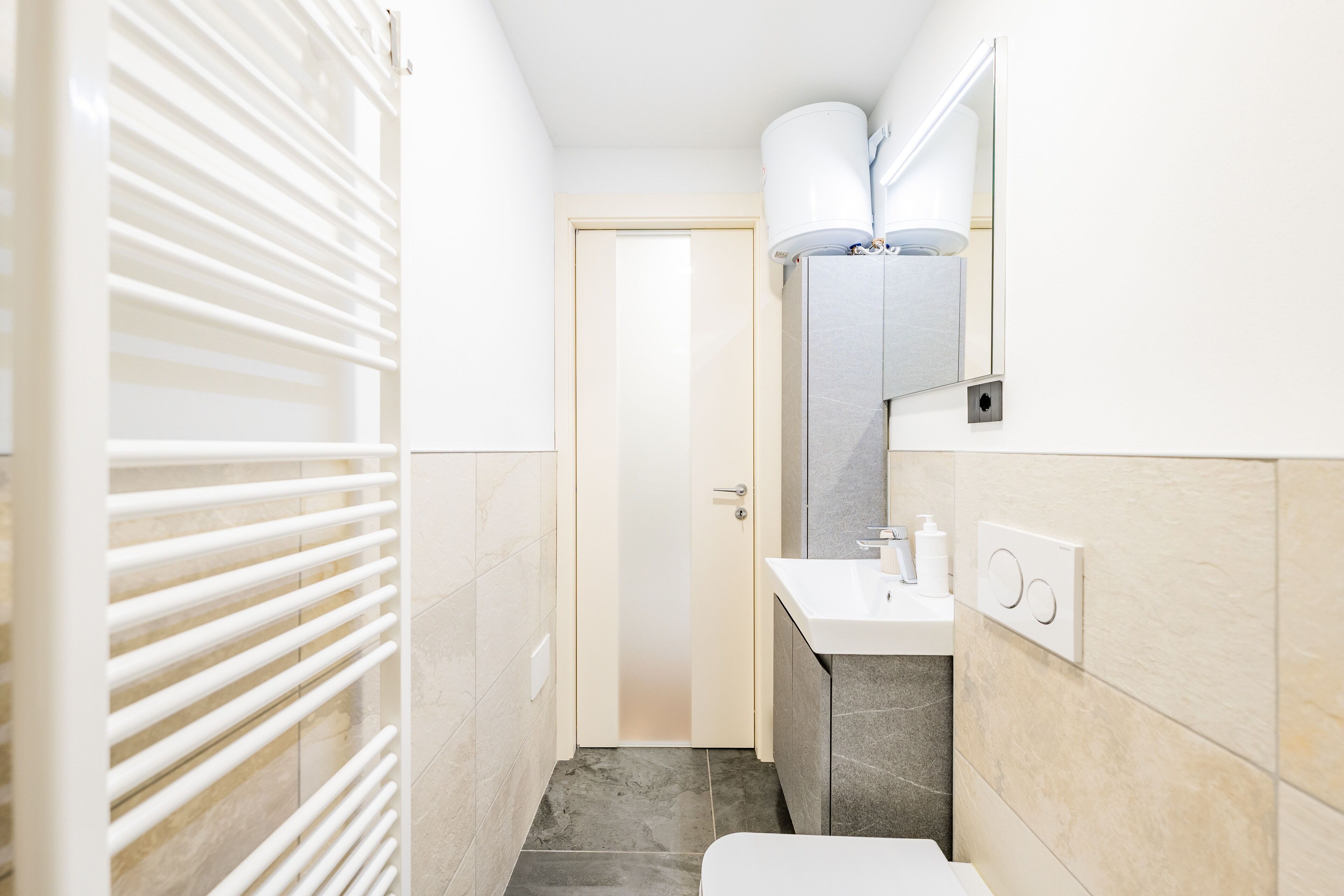 Ein schmales Badezimmer mit Toilette, Waschbecken und Handtuchhalter.