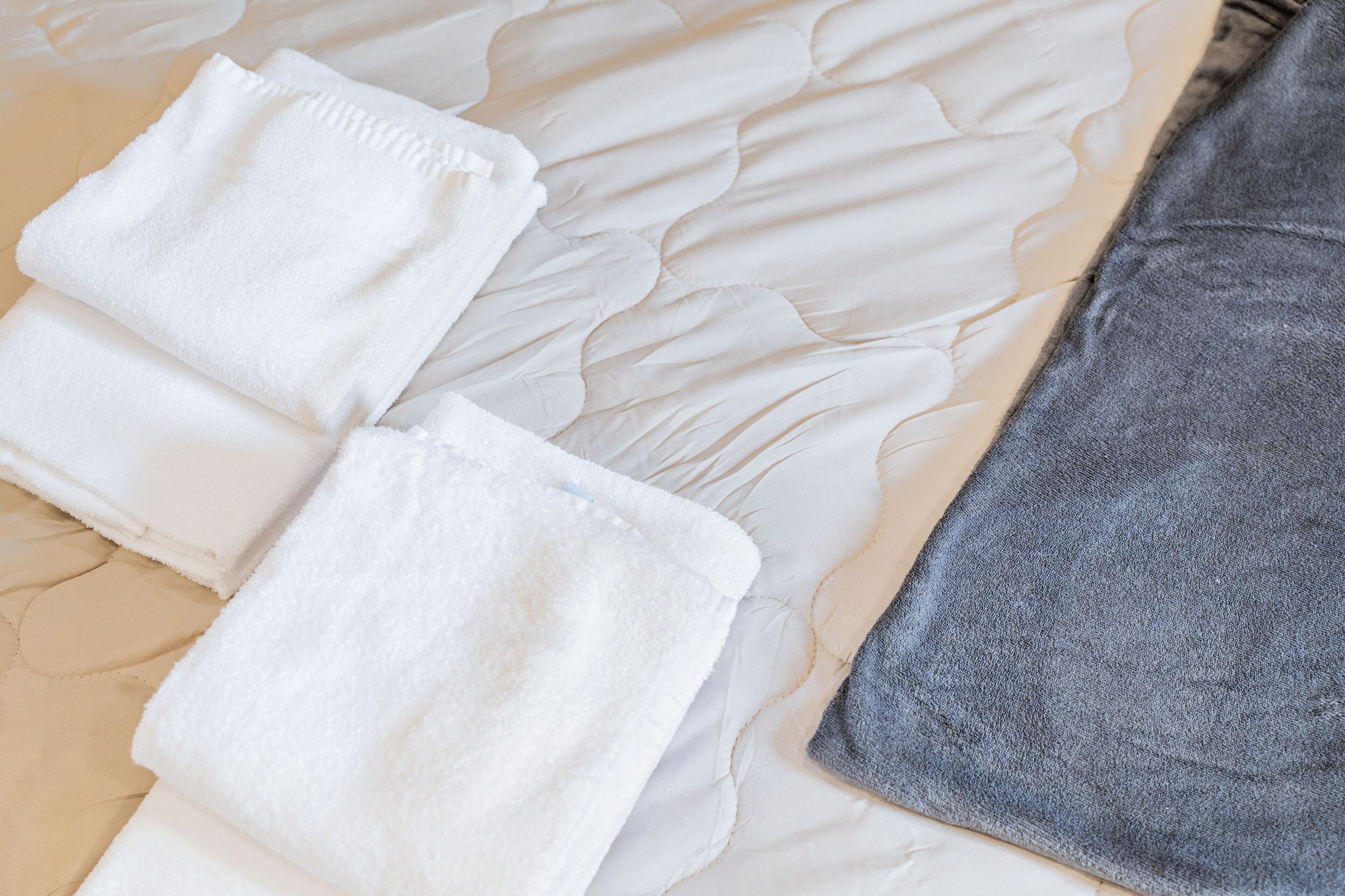 A neatly made bed with white and gray linens.