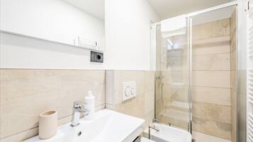 Ein modernes Badezimmer mit Waschbecken, Spiegel und einer Duschkabine aus Glas.