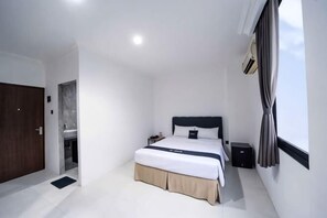 Un dormitorio con cama, mesita de noche y ventana con cortinas.