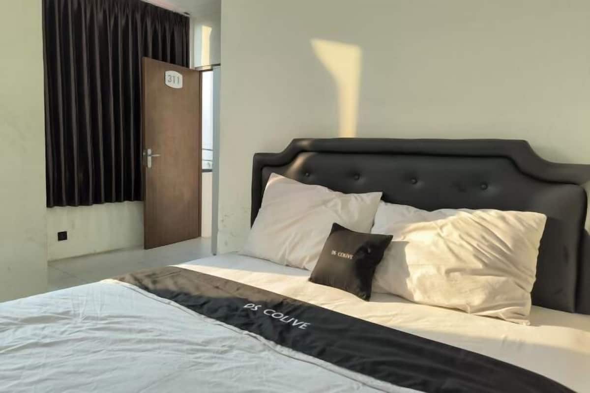 A bed with a black headboard, white and black bedding, and a sign on the wall.