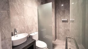 Uma casa de banho moderna com lavatório de mármore, sanita e cabine de duche em vidro.