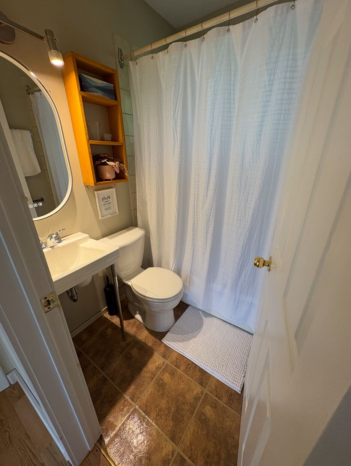 A compact bathroom with a toilet, sink, and a shower curtain.