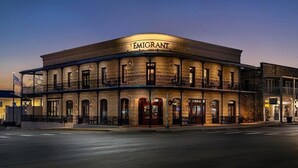 Un bâtiment historique doté d’une façade incurvée, d’une entrée imposante et d’un balcon aménagé avec des sièges pour l’extérieur.