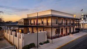 Un bâtiment à deux étages, doté d’un toit plat, d’une façade en pierre et d’un balcon à l’étage supérieur.