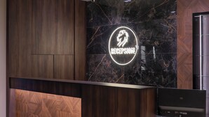 A reception desk with a marble wall, wooden paneling, and a neon sign. - Leo Hotel (Shtiqën)