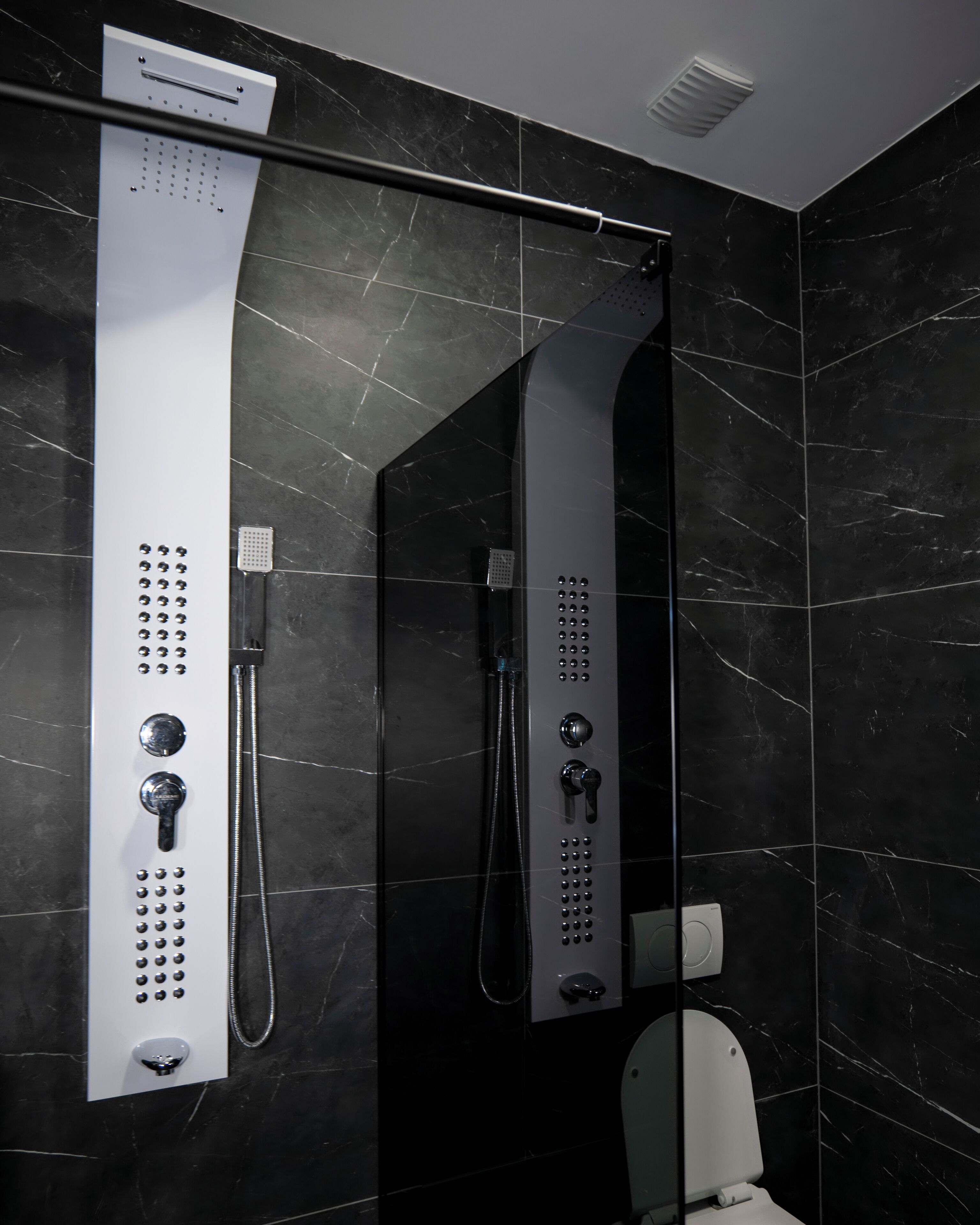 A modern bathroom with a glass-enclosed shower, a toilet, and a mirror.