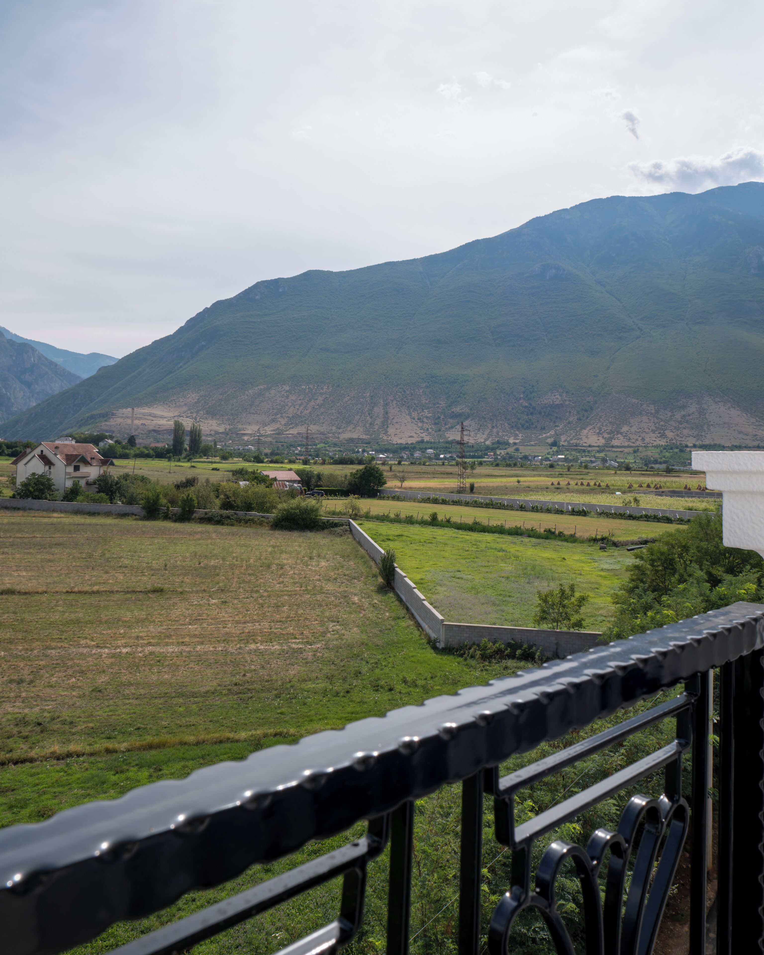 Paisaje rural con montañas, campos y una casa.